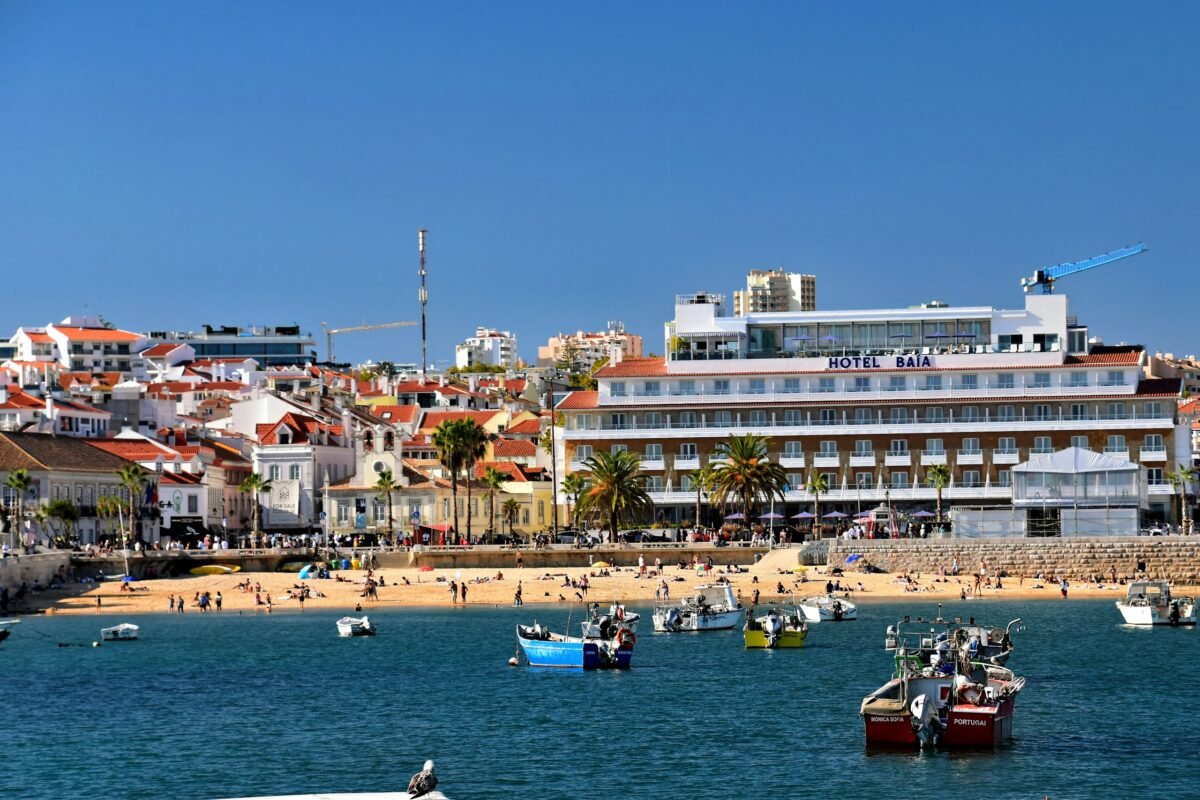 Fishing boats in Cascais Bay with the beach and waterfront behind them.