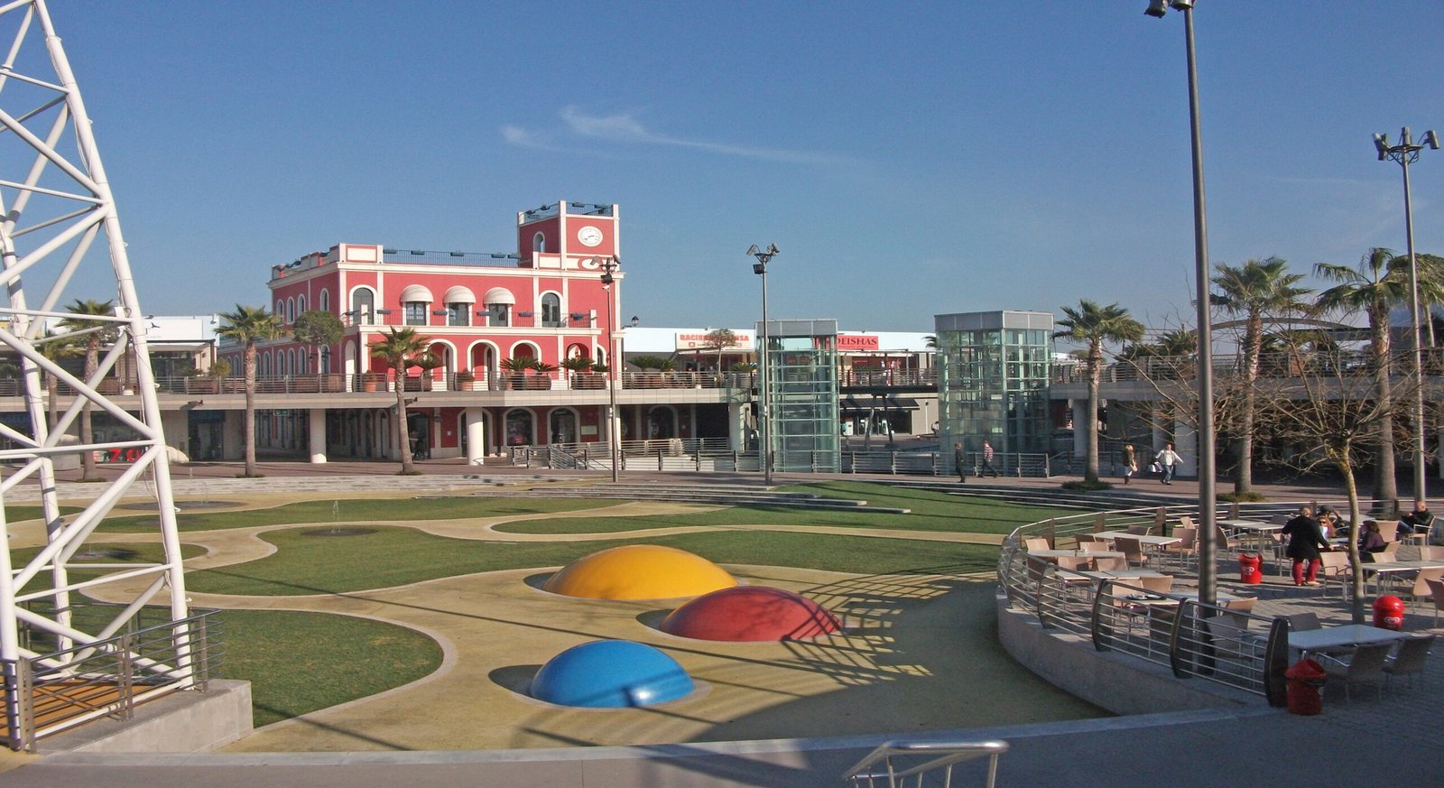 Patio central ajardinado con terrazas y cafeterías en la villa outlet de Alcochete