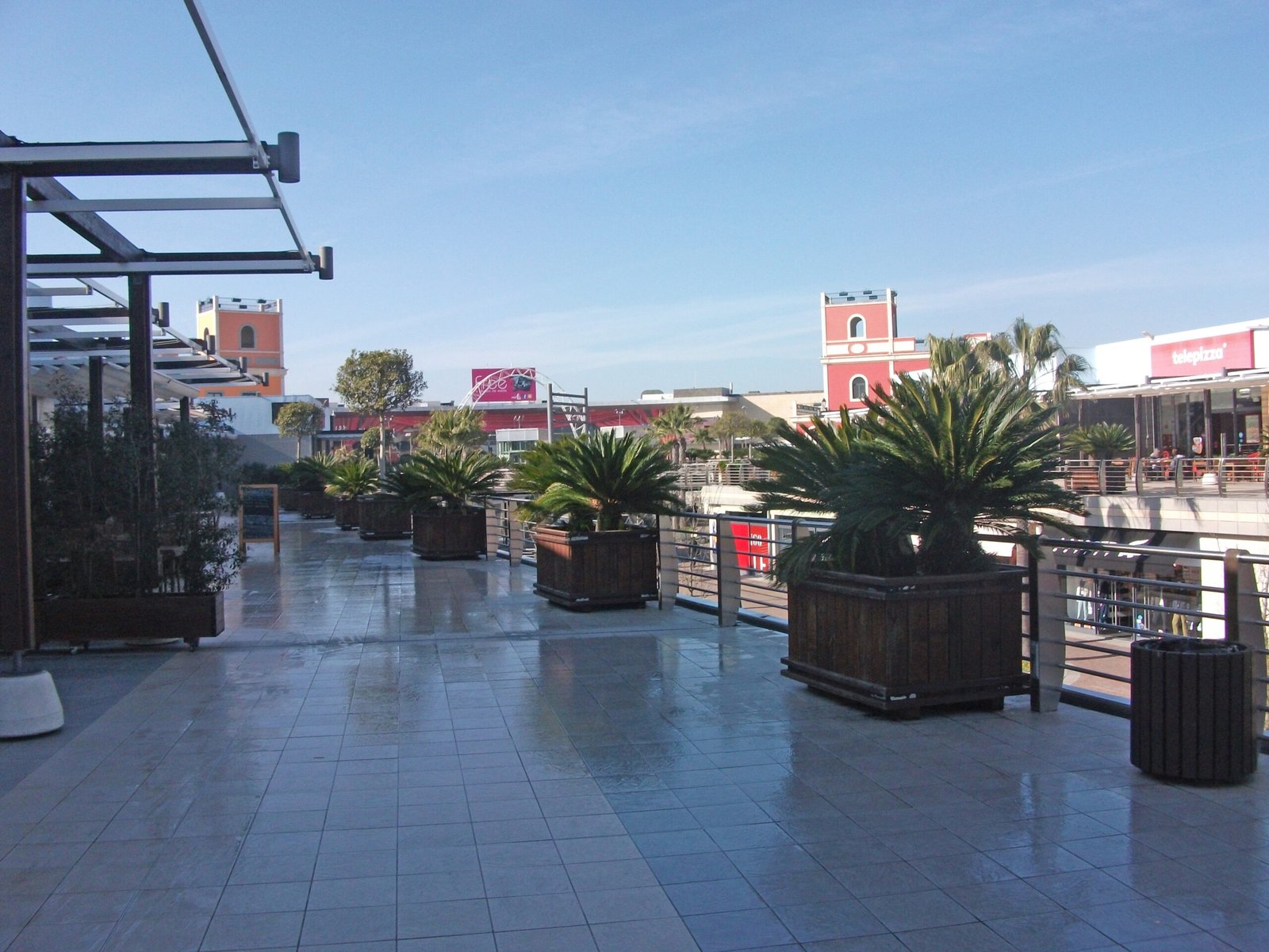 Alameda pedonal ao ar livre com montras de marcas de moda no Freeport Fashion Outlet