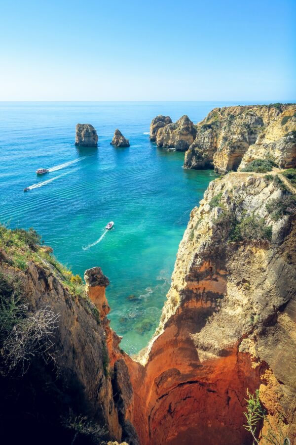 Boats pass golden cliffs and sea stacks at Ponta da Piedade, Lagos