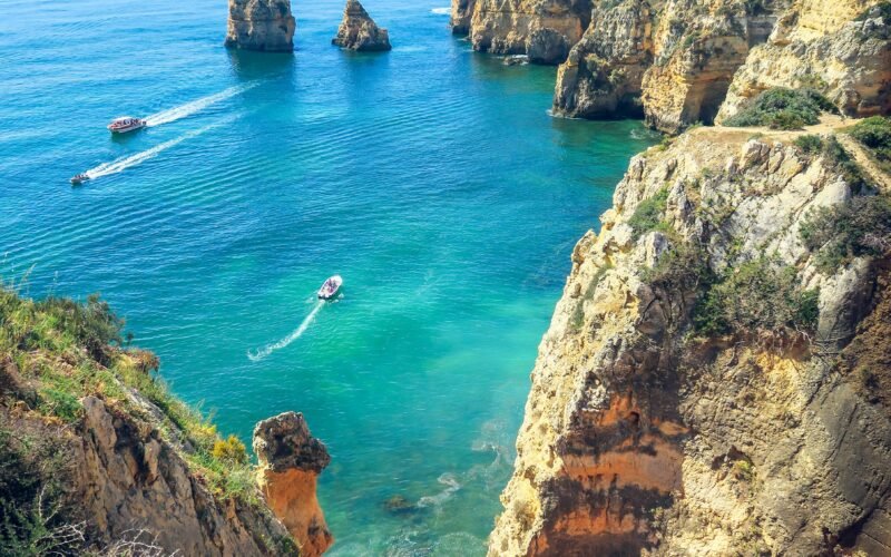 Boats pass golden cliffs and sea stacks at Ponta da Piedade, Lagos