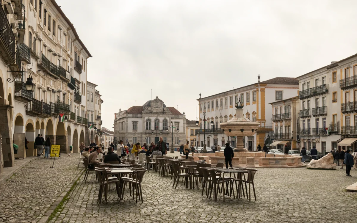 Outdoor cafés, historic arcades and fountain at Praça do Giraldo in Évora, Alentejo