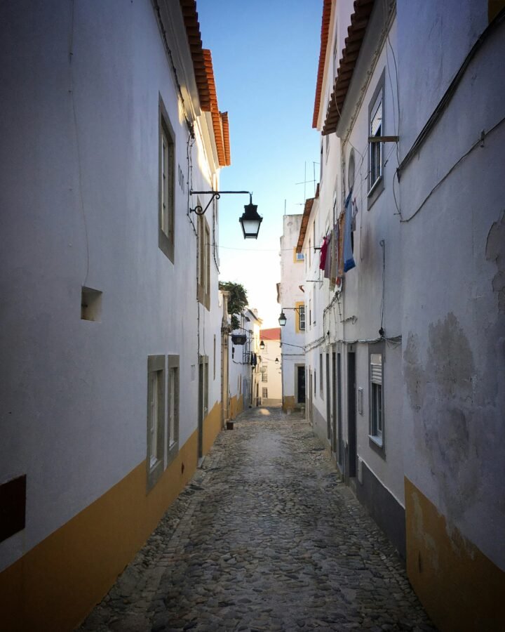 Narrow cobbled lane between whitewashed buildings in Évora