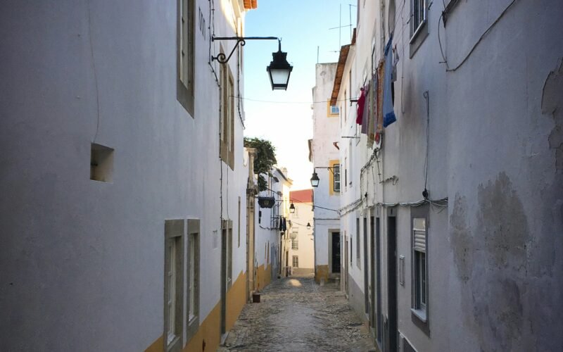 Rua estreita de calçada entre edifícios caiados em Évora