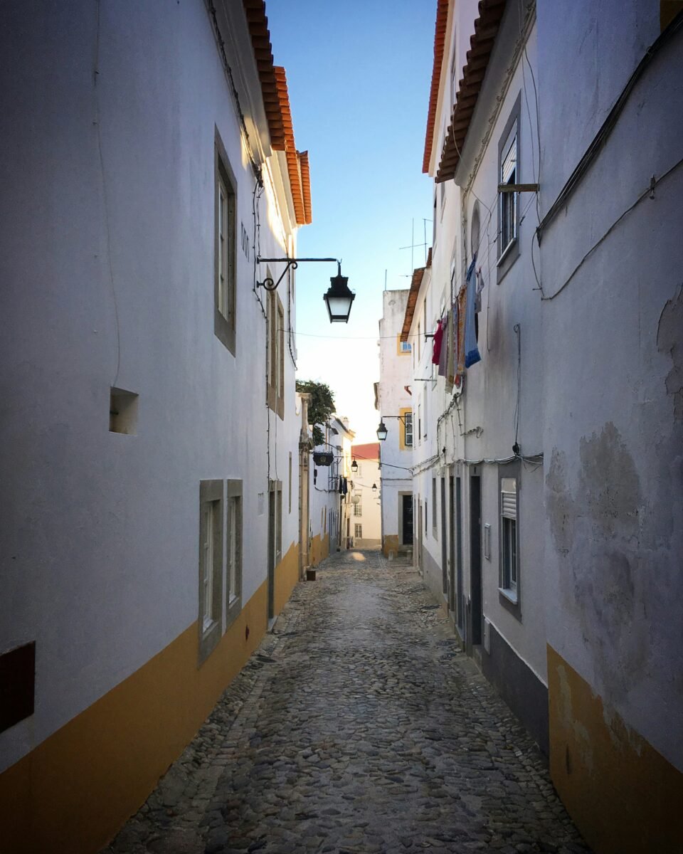 Narrow cobbled lane between whitewashed buildings in Évora