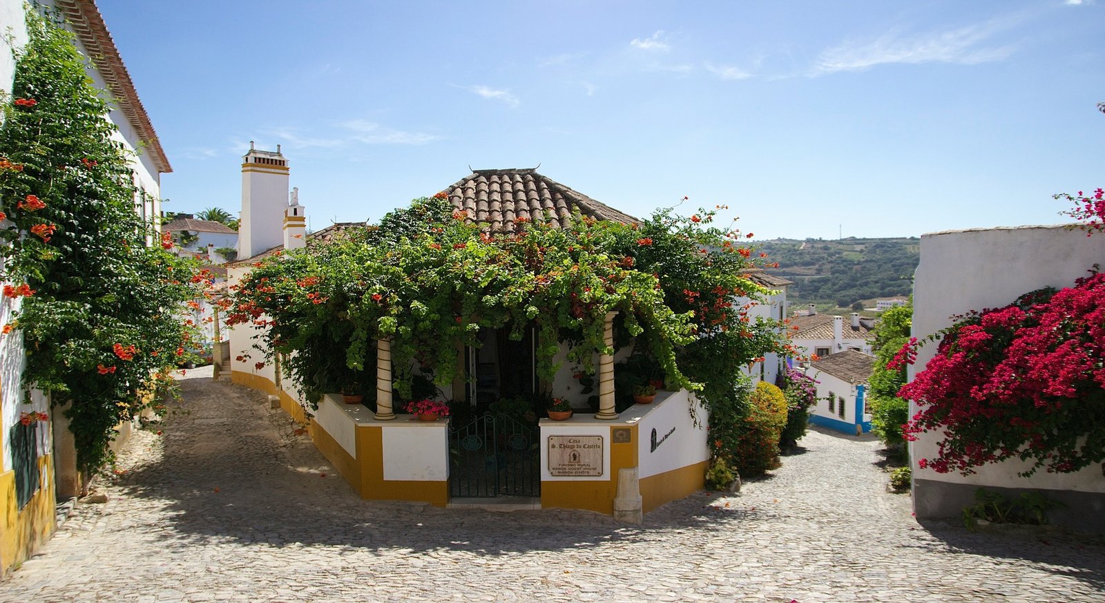Bougainvillea-draped cobbled street in medieval Óbidos