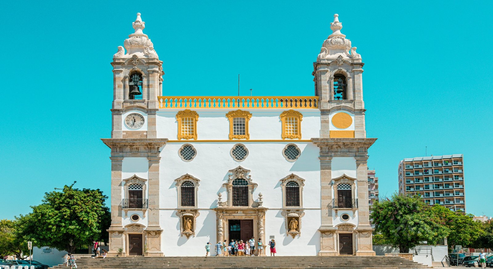 Fachada de uma igreja com duas torres e detalhes amarelos no Algarve
