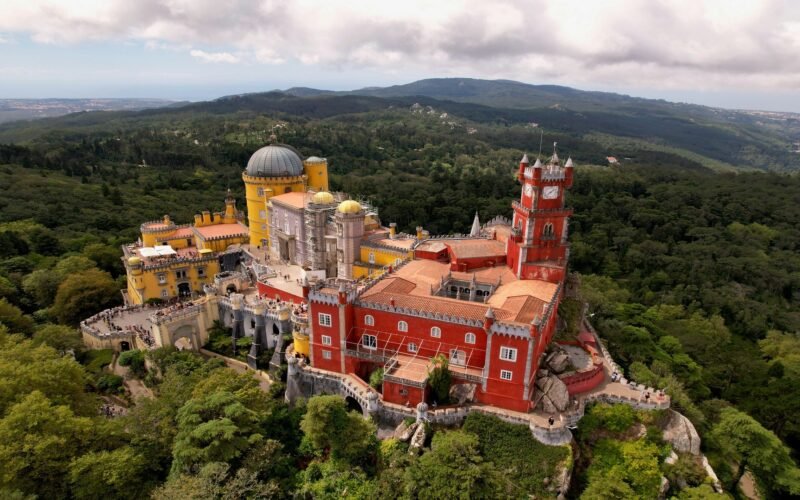 Torres coloridas do Palácio da Pena diante das colinas arborizadas de Sintra