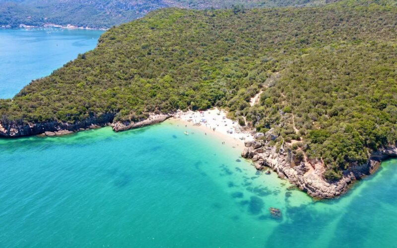 Vista aérea da costa arborizada da Arrábida e do mar turquesa junto a Setúbal