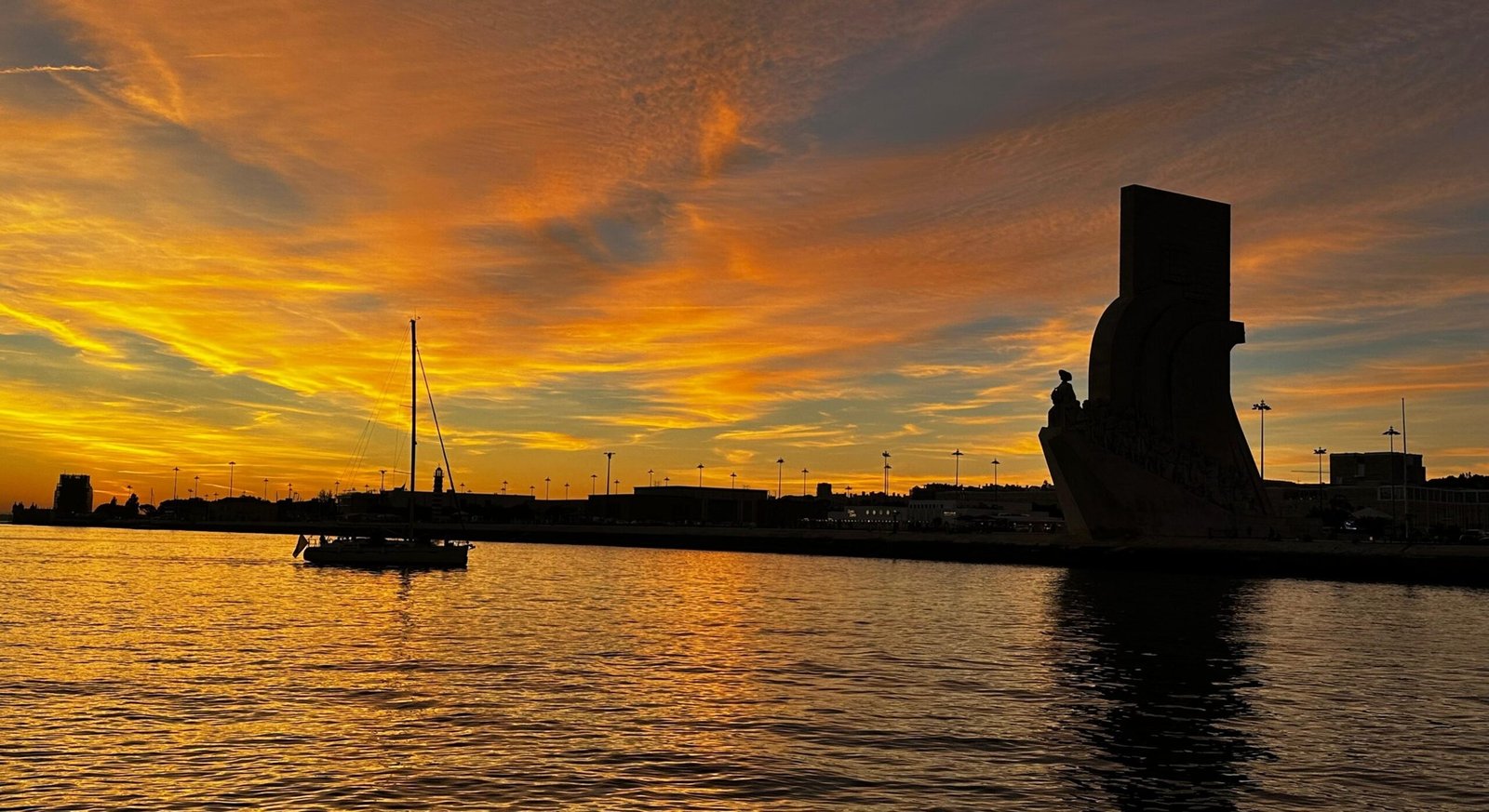 Golden sky over the Tagus with Belém Tower and a sailing boat