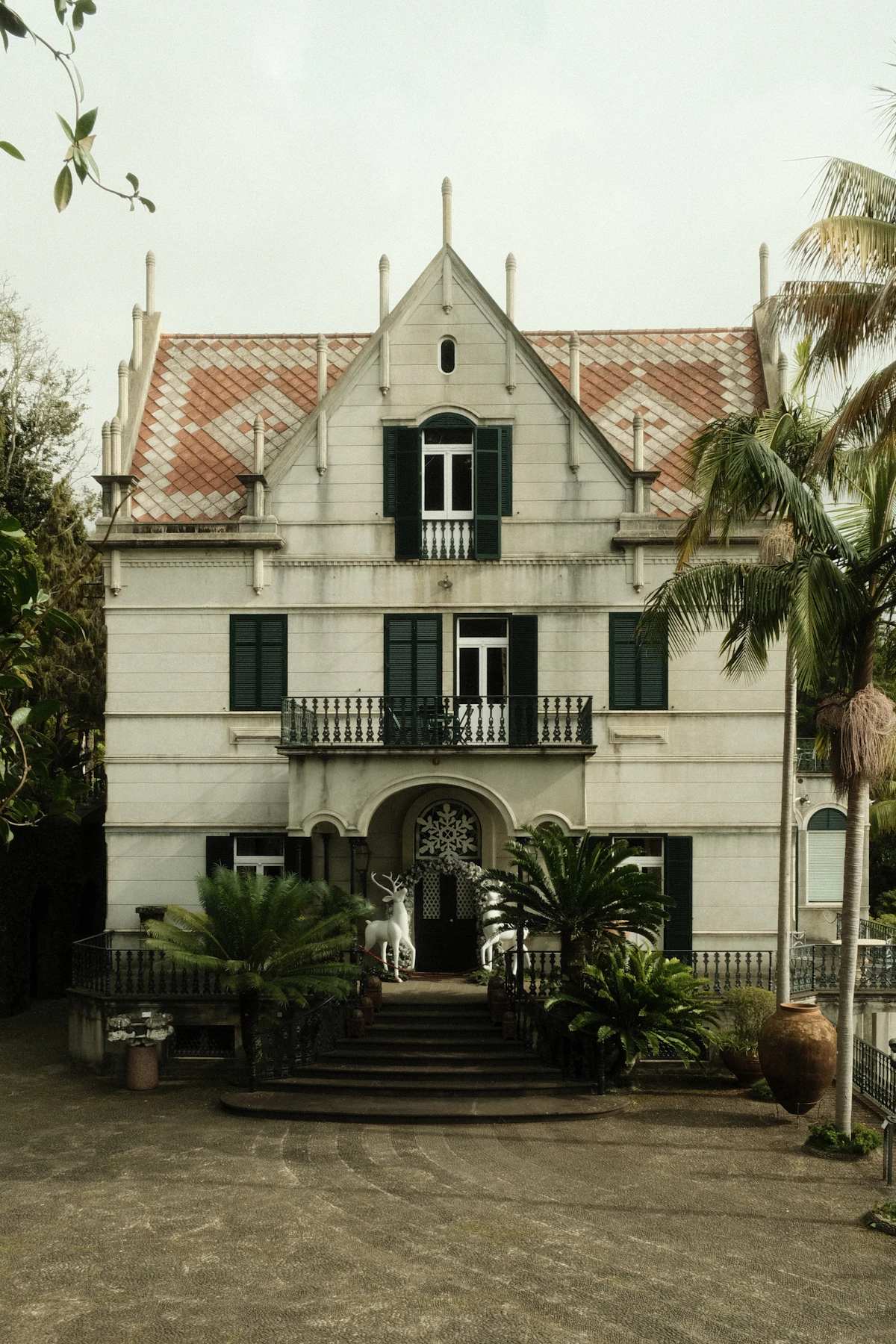 White façade, green shutters and palms at Monte Palace Madeira in Funchal