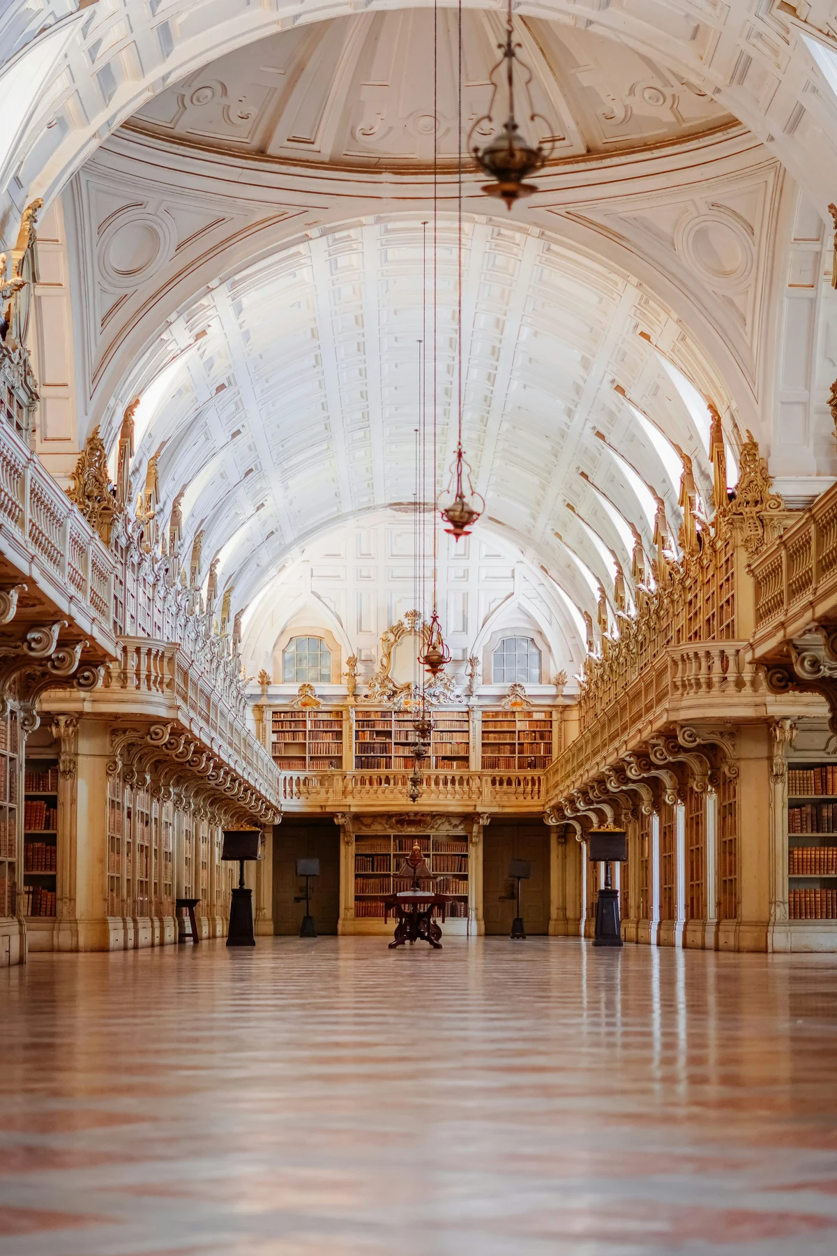 Vaulted white ceiling, carved bookshelves and patterned floor inside the library of Mafra National Palace