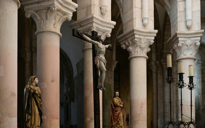 Crucifix and religious sculptures between stone columns inside Alcobaça Monastery