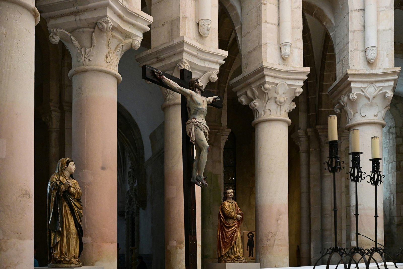 Crucifix and religious sculptures between stone columns inside Alcobaça Monastery