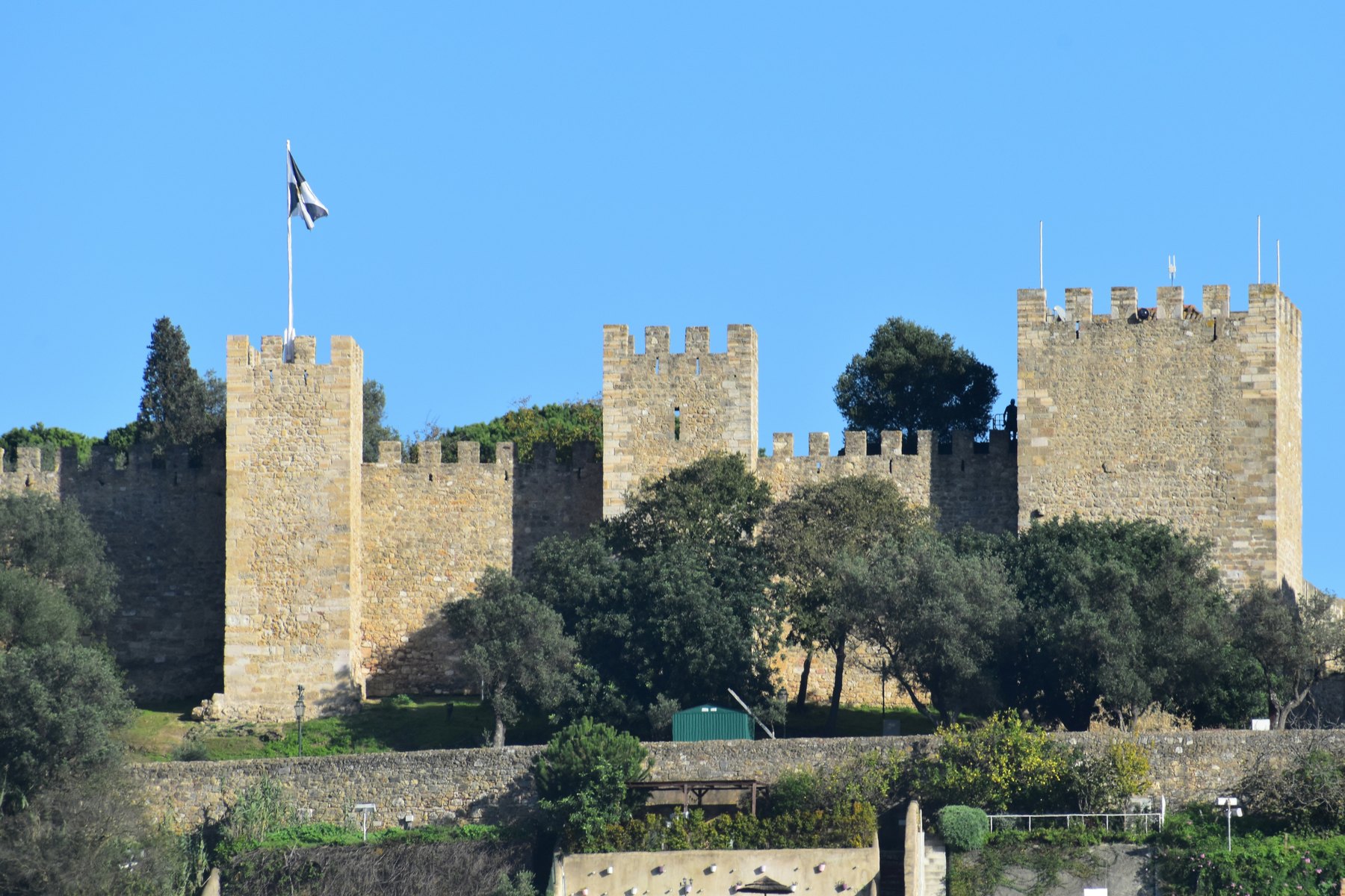 Battlemented walls and towers of São Jorge Castle beneath a blue Lisbon sky