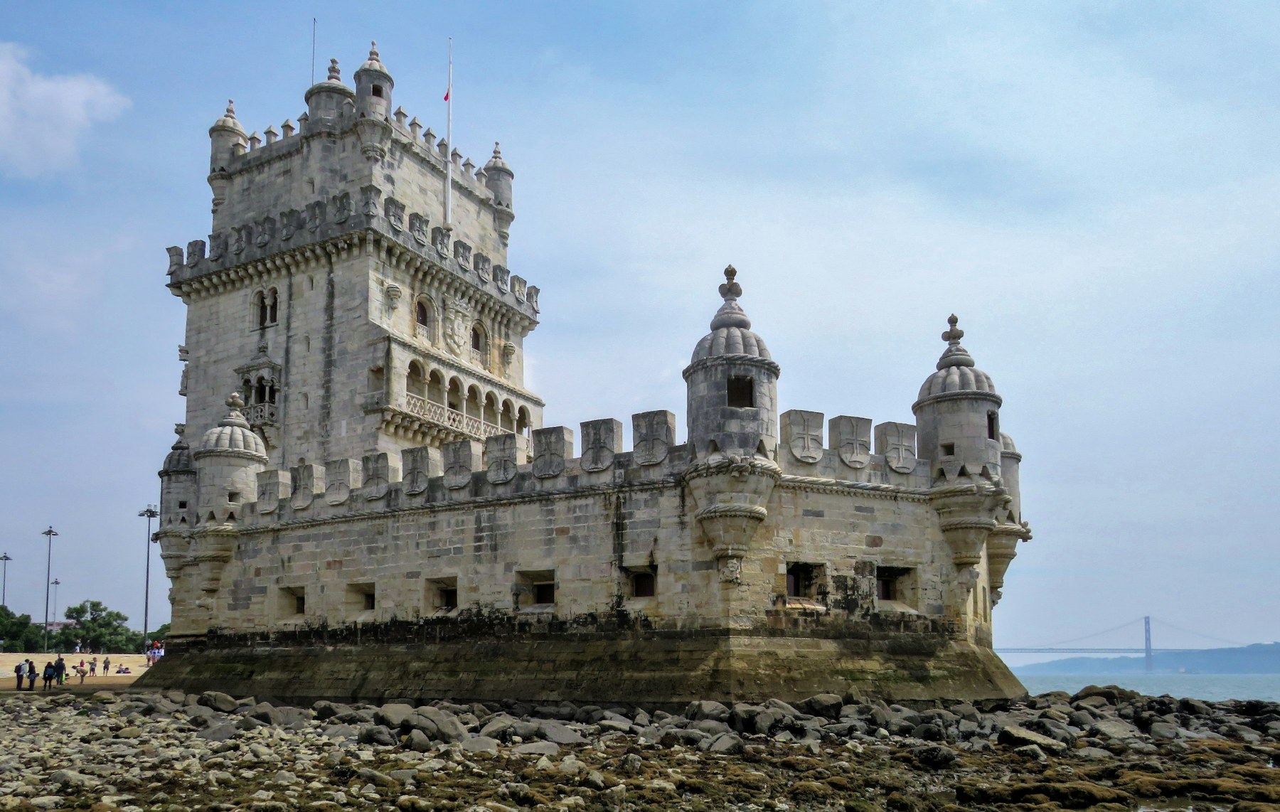 Rear view of Belém Tower at low tide on the Tagus riverbank.