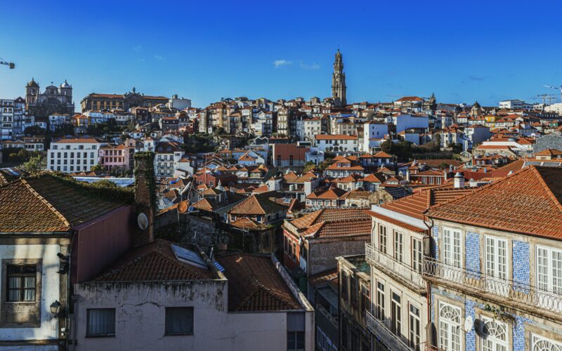 Clérigos Tower rising above Porto’s terracotta rooftops under a blue sky.