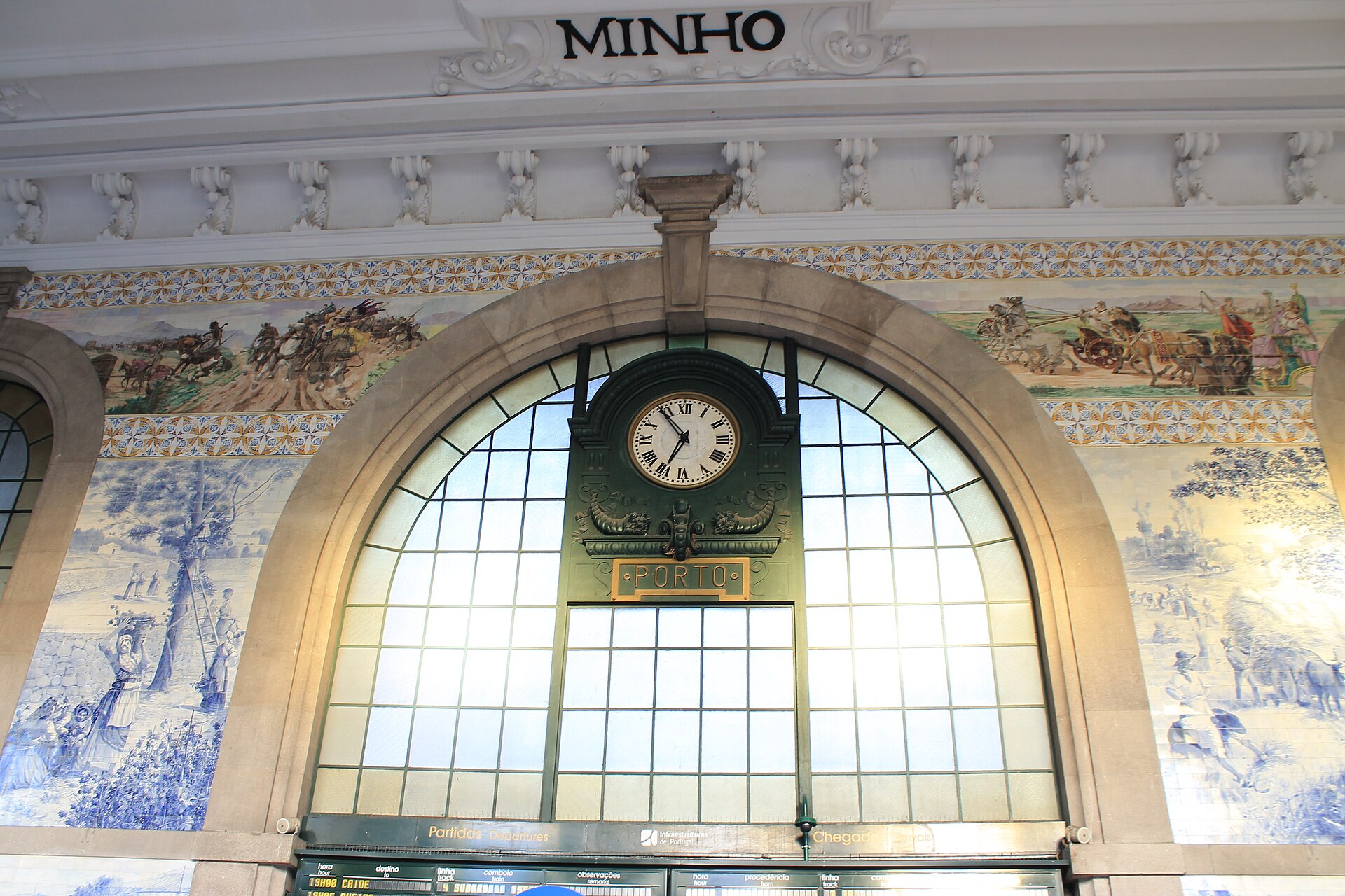 Clock, arched window and azulejo panels in São Bento station in Porto