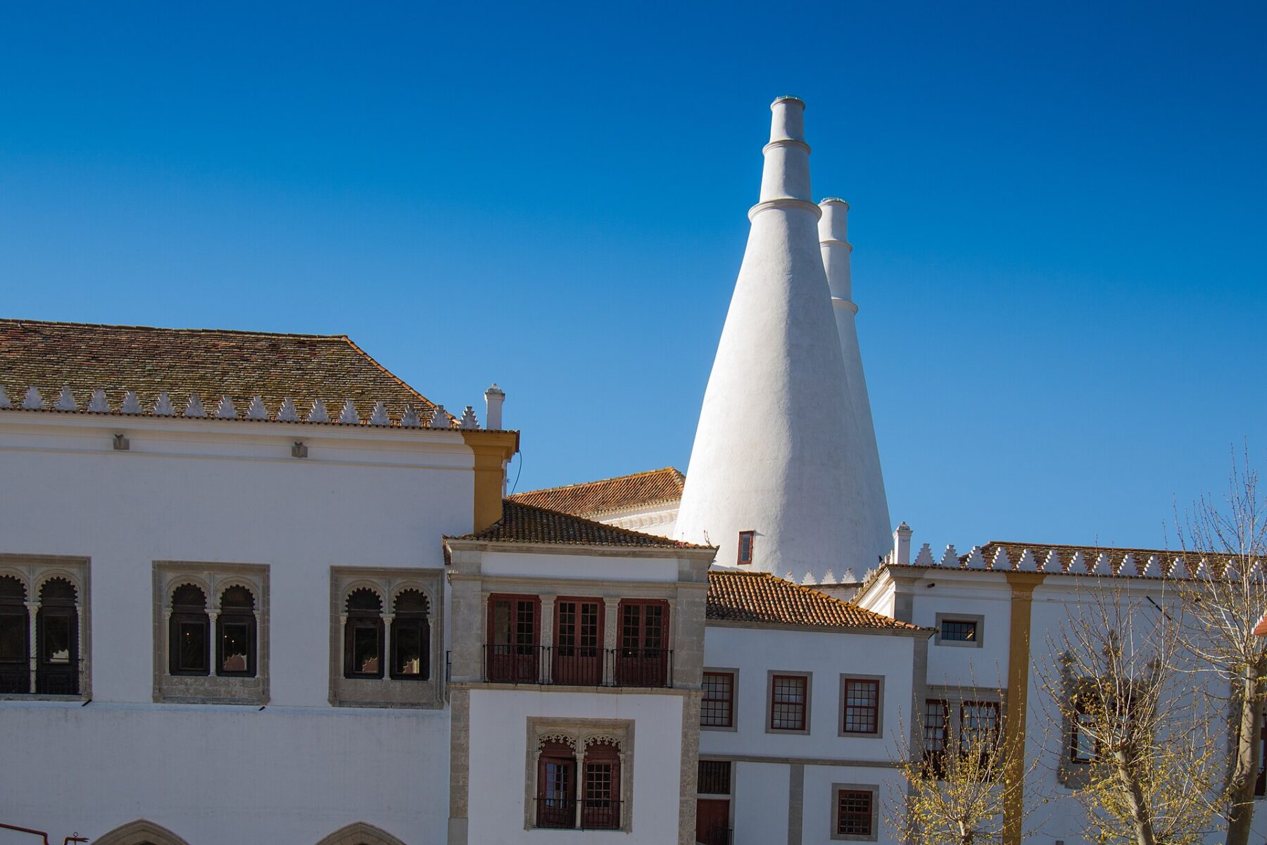 Twin white kitchen chimneys above the National Palace of Sintra