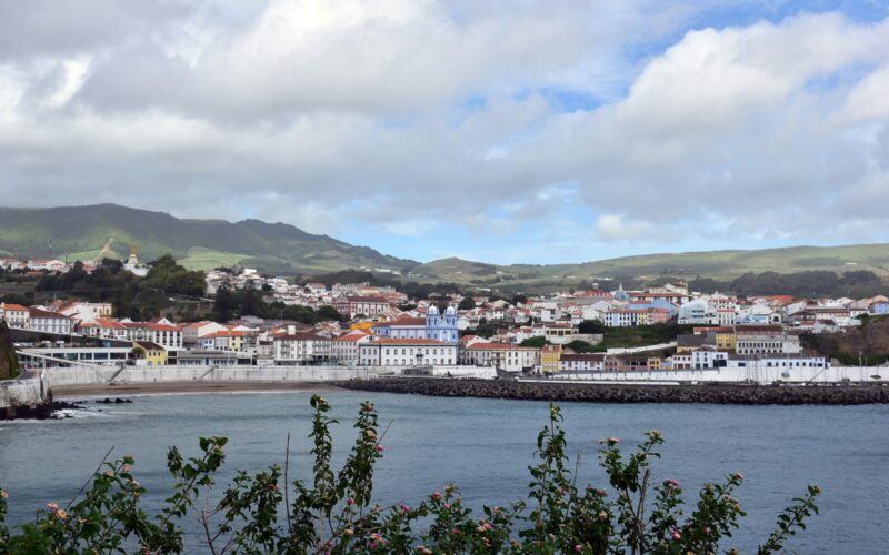 Waterfront of Angra do Heroísmo with the blue church façade and tiled roofs under clouds