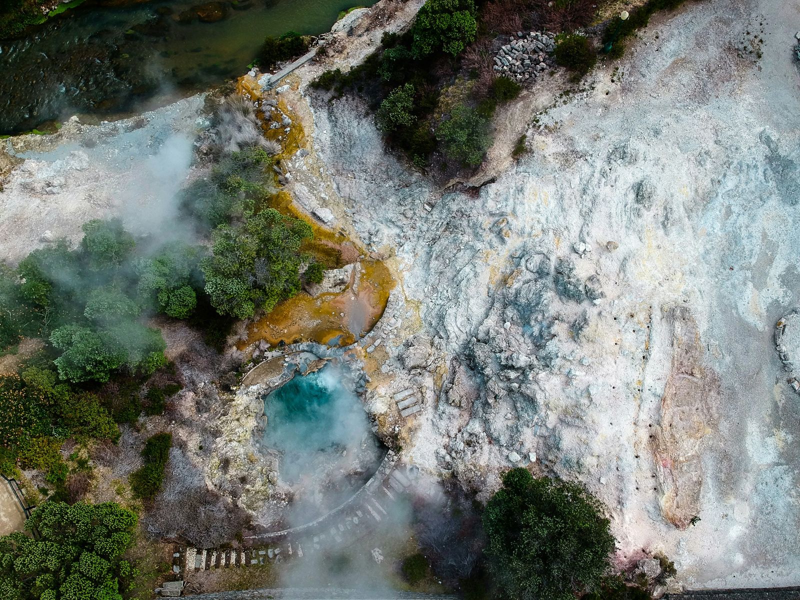 Aerial view of steaming mineral-coloured pools and visitor paths in Furnas