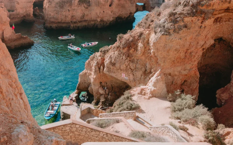 Costa rochosa do Algarve perto de Lagos, com pequenos barcos em águas azul-turquesa